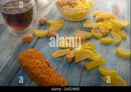Ein Glas schwarzen Tee, Kuchen und Marmelade Zitronenscheiben auf einer hölzernen Hintergrund Stockfoto