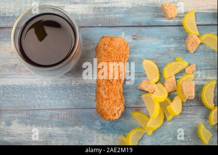 Ein Glas schwarzen Tee, Kuchen und Marmelade Zitronenscheiben auf einer hölzernen Hintergrund Stockfoto