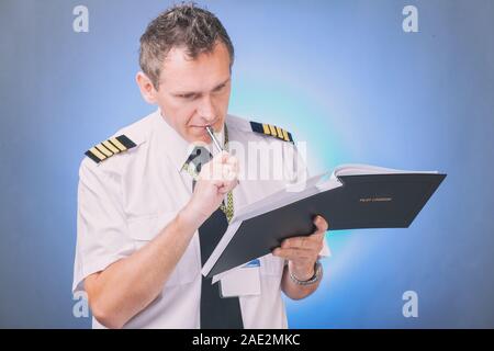 Airline Pilot tragen Shirt mit Schulterklappen und Riegel ausfüllen Füllen und Kontrolle der Papiere Logbuch und Prüfung der Papiere und Wettervorhersage Stockfoto