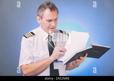 Airline Pilot tragen Shirt mit Schulterklappen und Riegel ausfüllen Füllen und Kontrolle der Papiere Logbuch und Prüfung der Papiere und Wettervorhersage Stockfoto