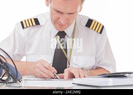 Airline Pilot tragen Shirt mit Schulterklappen und Riegel ausfüllen Füllen und Kontrolle der Papiere Logbuch und Prüfung der Papiere und Wettervorhersage Stockfoto