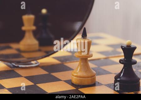 Zwei Schachfiguren König und die Königin auf dem Schachbrett und ihre Reflexion in den Spiegel. Stockfoto