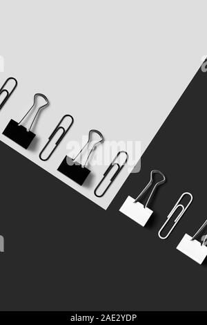Schwarz und Weiß Büroartikel, Büroklammern und binder clips sauber über schwarzen und weißen Hintergrund organisiert, Ansicht von oben Stockfoto
