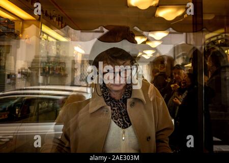LUCCA, Italien - 24. NOVEMBER 2019: unbekannte Frau liest die Zeitung aus dem Fenster einer Bar in der Via Elisa Stockfoto