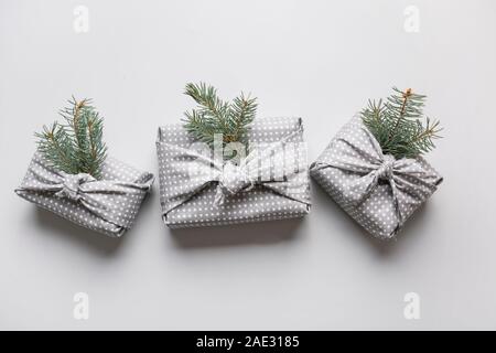 Weihnachten umweltfreundliche Geschenk in Rot und Grau Textil mit natürlichen Dekor gewickelt. Nachhaltige Geschenke. Null Abfall. Xmas eco Urlaub. Traditionelle Japanische Stockfoto