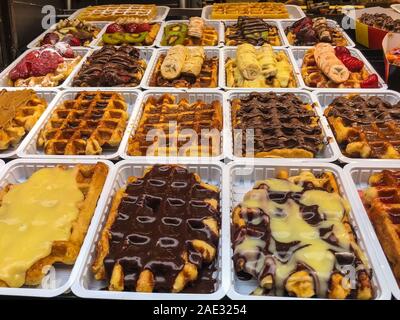 Traditionelle belgische Waffeln mit dem Geschmack der verschiedenen Marmeladen, Pralinen, Obst und Beeren sind auf dem Markt für Touristen und Einheimische auf einem sonnigen d verkauft Stockfoto