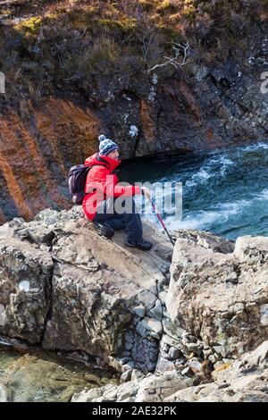 Mann sitzt auf Felsen an Fairy Pools, Fluss Spröde, Isle of Skye, Schottland, UK im März Stockfoto