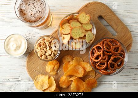 Chips, Bier, Bier, Snacks, Bier, Muttern, Saucen auf weißem Hintergrund Holz, Platz für Text. Ansicht von oben Stockfoto