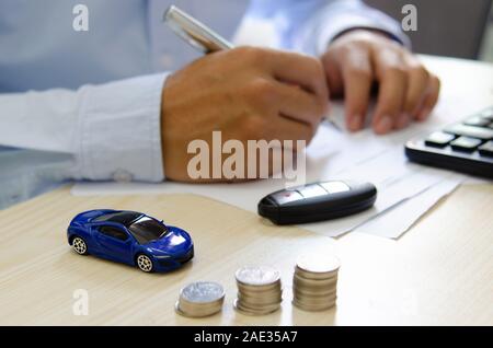 Spielzeug Auto finance Calculator, Autoschlüssel und Papiere auf dem Schreibtisch. Auto Versicherung Konzept Stockfoto