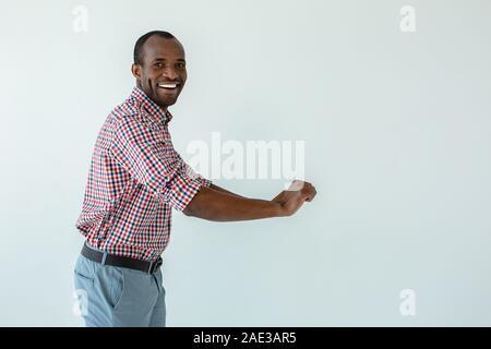 Freudige afro-amerikanische Mann schieben die Karre gegen weißen Hintergrund Stockfoto
