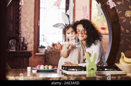 Mit Bürsten in die Hände. Großmutter und Enkelin haben sie Spaß in der Küche zu Ostern Stockfoto