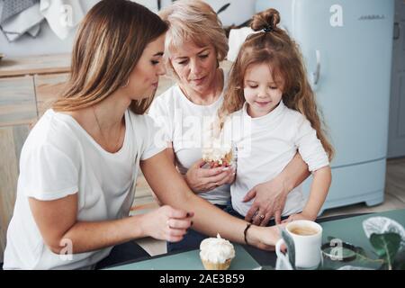 Kaffee und Süßes essen. Mutter, Großmutter und Tochter eine gute Zeit in der Küche Stockfoto