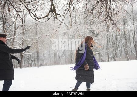 Exakte Treffer in das Gesicht des Mädchens. Wunderschöne junge Paar spielen und das Werfen mit Schneebällen im Winter Wald Stockfoto