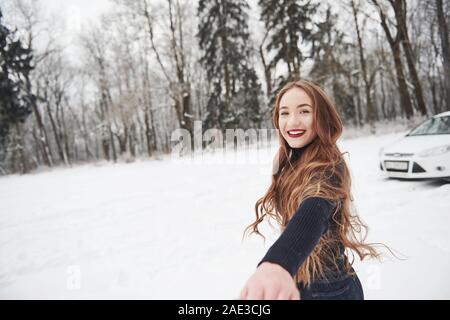 Ich weiß, wo wir hin gehen. Mädchen mit langen Haaren geht in der Nähe des Waldes auf die Automobilindustrie im Winter Stockfoto