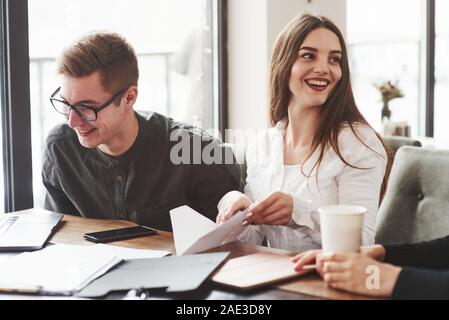 Mädchen macht Paper Plane. Junge Studenten, die auf dem Projekt arbeiten beim Sitzen im Zimmer in der Nähe der Fenster Stockfoto