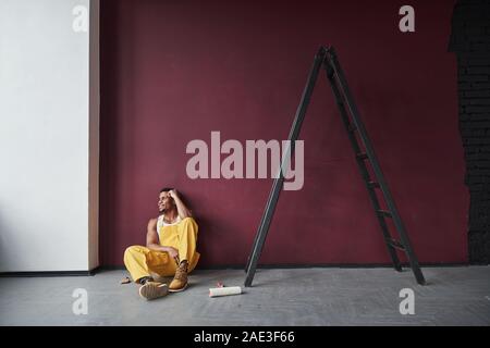 Es war leicht. Junge afrikanische amerikanische Arbeiter, die in den gelben Uniform haben einige Job Stockfoto