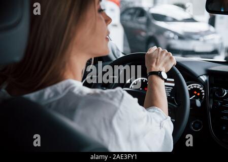 Auf der Umdrehungen vorsichtig sein. Schöne blonde Mädchen in der neuen Auto sitzen mit modernen schwarzen Interieur Stockfoto