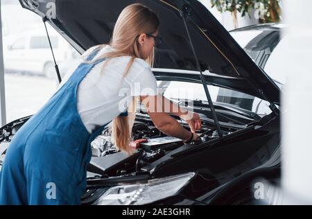 Dabei hart arbeiten. Auf der schönen Job. Auto süchtig Frau Reparaturen schwarz Automobil im Innenbereich Stockfoto