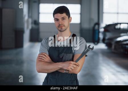 Ruhig und konzentriert. Portrait von ernsthaften Arbeiter in Uniform, die in seinem Workshop mit dem Schraubenschlüssel in der Hand steht Stockfoto