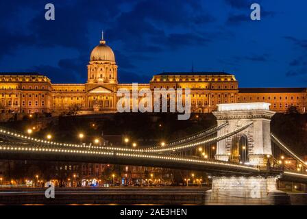 Royal Palace oder die Budaer Burg und der berühmten Kettenbrücke nach Sonnenuntergang mit Lichtern in der Donau in Budapest Ungarn beleuchtet. Stockfoto