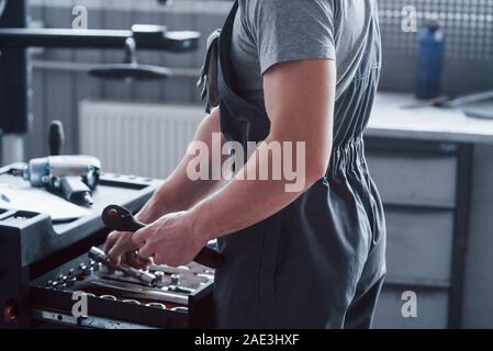 Alles ist in Ordnung. Seite Nahaufnahme des Arbeitnehmers, die für die benötigten Werkzeuge für Auto Reparatur sieht Stockfoto