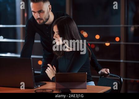 In Schwarz tragen. Team der jungen Unternehmer arbeitet an ihrem Projekt in der Nacht im Büro Stockfoto