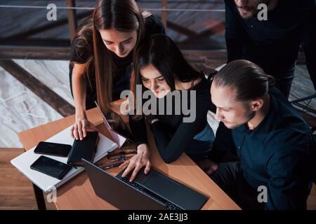 Scrollen der Dokumente auf dem Laptop. Team der jungen Unternehmer arbeitet an ihrem Projekt in der Nacht im Büro Stockfoto