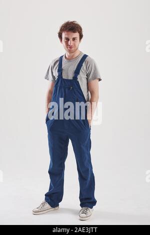 Mann in der blauen Uniform steht vor weißem Hintergrund im Studio Stockfoto