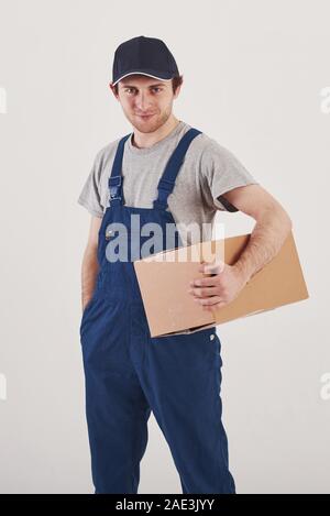 Ihre Bestellung ist hier. Kerl mit Box in den Händen steht vor weißem Hintergrund im Studio Stockfoto