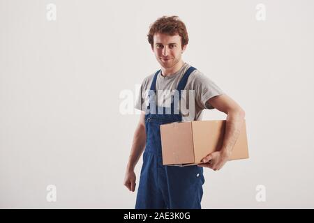 Kerl mit Box in den Händen steht vor weißem Hintergrund im Studio Stockfoto