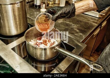 Behandschuhten Koch ist das Hinzufügen von belasteten Tomaten in eine Schüssel, professionelle Küche, getönten Foto, HDR Stil Stockfoto