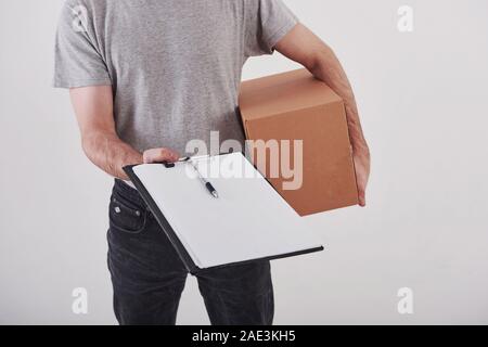 Leeres Papier. Kerl mit Box in den Händen steht vor weißem Hintergrund im Studio Stockfoto