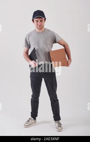 Kunde wartet auf mich. Kerl mit Box in den Händen steht vor weißem Hintergrund im Studio Stockfoto