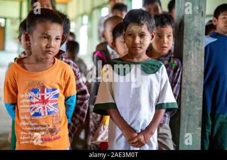 Junge Studenten mit Gepuderten Gesichter Line up Songs auf einer Versammlung zu Singen in einem ländlichen Dorf Schule entlang der Chindwin Fluss in Myanmar (Birma) Stockfoto