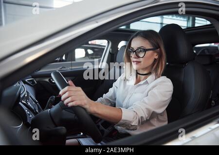 Schöne blonde Mädchen in der neuen Auto sitzen mit modernen schwarzen Interieur Stockfoto
