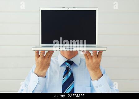 Nicht erkennbare Geschäftsmann holding Laptop vor seinen Kopf mit der leere Bildschirm Austausch sein Gesicht Stockfoto