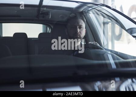 In den Job. Vorderansicht des junge Bartgeier Geschäftsmann in seinem Luxus schwarz Auto sitzen Stockfoto