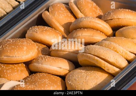 Hamburger Brötchen in Scheiben geschnitten auf einer Aluminiumschale, bereit, Burger zu kochen. Stockfoto