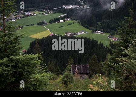 Schöner Panoramablick auf die ländliche alpine Landschaft mit Kühe grasen in frischen grünen Wiesen neath schneebedeckten Gipfeln an einem sonnigen Tag im Frühjahr, N Stockfoto