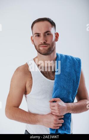 Die Dusche. Mann mit blauen Handtuch steht vor weißem Hintergrund im Studio Stockfoto