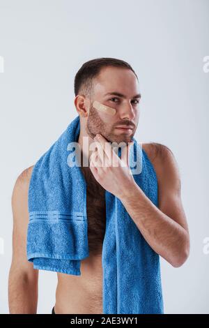 Gerade aus der Dusche. Mann mit blauen Handtuch steht vor weißem Hintergrund im Studio Stockfoto