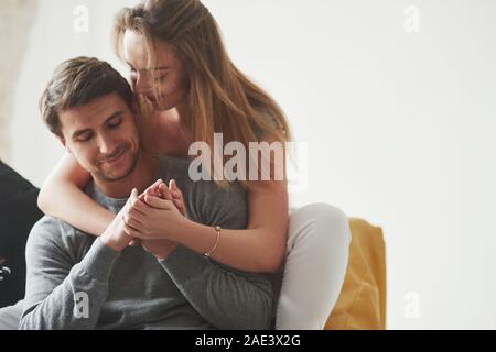 Nähe und Liebe. Glückliches Paar entspannende auf dem gelben Sofa im Wohnzimmer ihres neuen Hauses Stockfoto