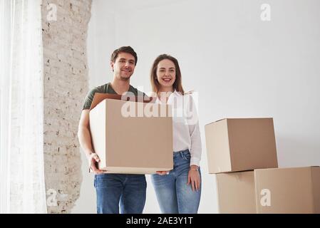 Stand vor der Kamera. Holding Box mit Elementen. Familie Umzug in neues Haus Stockfoto