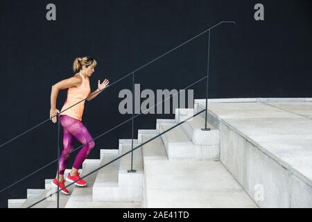 Junge sportliche Frau in Sportkleidung auf Treppen im Außenbereich verkleidet. Stockfoto