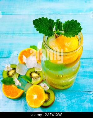 Detox Wassercocktail. Gesundheitsgetränk mit Eis Kiwi und Orange auf blauem Holzhintergrund, Schlankheitskur Stockfoto