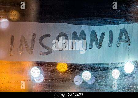 Das Wort Schlaflosigkeit auf Nacht nasse Fenster schließen geschrieben mit unscharfem Hintergrund. Stockfoto
