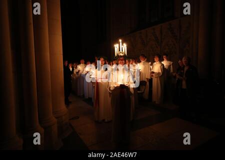 Matilda Bergstrom eine Krone trägt der Kerzen symbolisieren St Lucy, führt ein Abendessen bei Kerzenschein Prozession der London Nordic Chor während der Sankta Lucia service an der York Minster. Bild Datum: Freitag Dezember 6, 2019. Die atmosphärischen Schwedische Service ist eine Feier der St. Lucy, ein sizilianisches mädchen für ihren christlichen Glauben im vierten Jahrhundert den Märtyrertod. Die Krone symbolisiert ein Halo, einer roten Schärpe ihr Martyrium und der Service feiert das Mitbringen von Licht in der Dunkelheit des Winters. Photo Credit: Danny Lawson/PA-Kabel Stockfoto