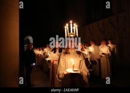 Matilda Bergstrom eine Krone trägt der Kerzen symbolisieren St Lucy, führt ein Abendessen bei Kerzenschein Prozession der London Nordic Chor während der Sankta Lucia service an der York Minster. Bild Datum: Freitag Dezember 6, 2019. Die atmosphärischen Schwedische Service ist eine Feier der St. Lucy, ein sizilianisches mädchen für ihren christlichen Glauben im vierten Jahrhundert den Märtyrertod. Die Krone symbolisiert ein Halo, einer roten Schärpe ihr Martyrium und der Service feiert das Mitbringen von Licht in der Dunkelheit des Winters. Photo Credit: Danny Lawson/PA-Kabel Stockfoto