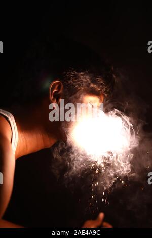 Junger Mann mit brennenden Wunderkerzen Feuerwerk am Mund Stockfoto