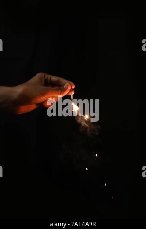 Hand, die brennende Wunderkerze Blast auf schwarzem Hintergrund Stockfoto